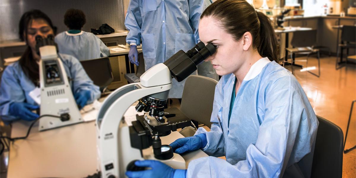 AACC student with microscope in lab