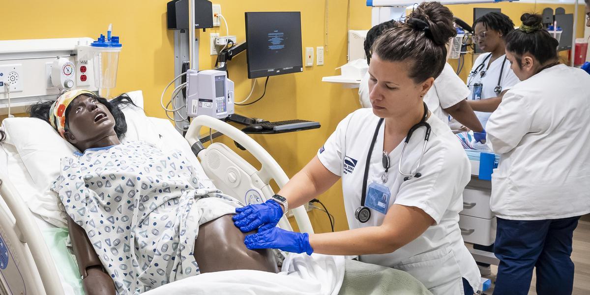 Nursing student working with pregnant manikin.