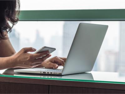 Student uses computer with her smart phone.