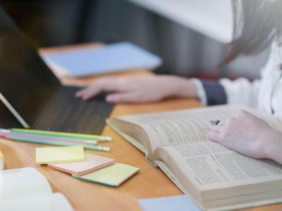 Student refers to textbook and laptop.